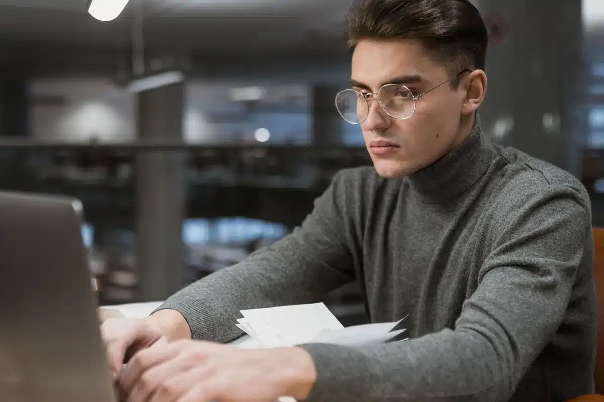 Studente universitario che lavora al laptop in una camera da letto del dormitorio con libri e appunti