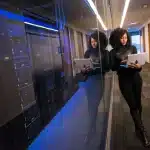 Sala server con file di unità di memorizzazione e mani di un tecnico che lavora su componenti hardware