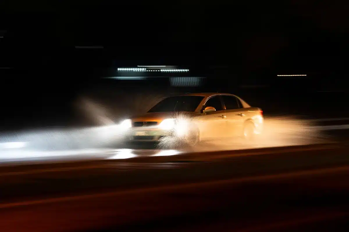 Fascio di luce di fari auto intenso su strada buia notturna