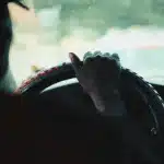 Mani di un autista sul volante con schermo del telefono spento e inattivo