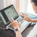 Mani anonime su un portatile con codice e icone di portafoglio digitale sullo schermo