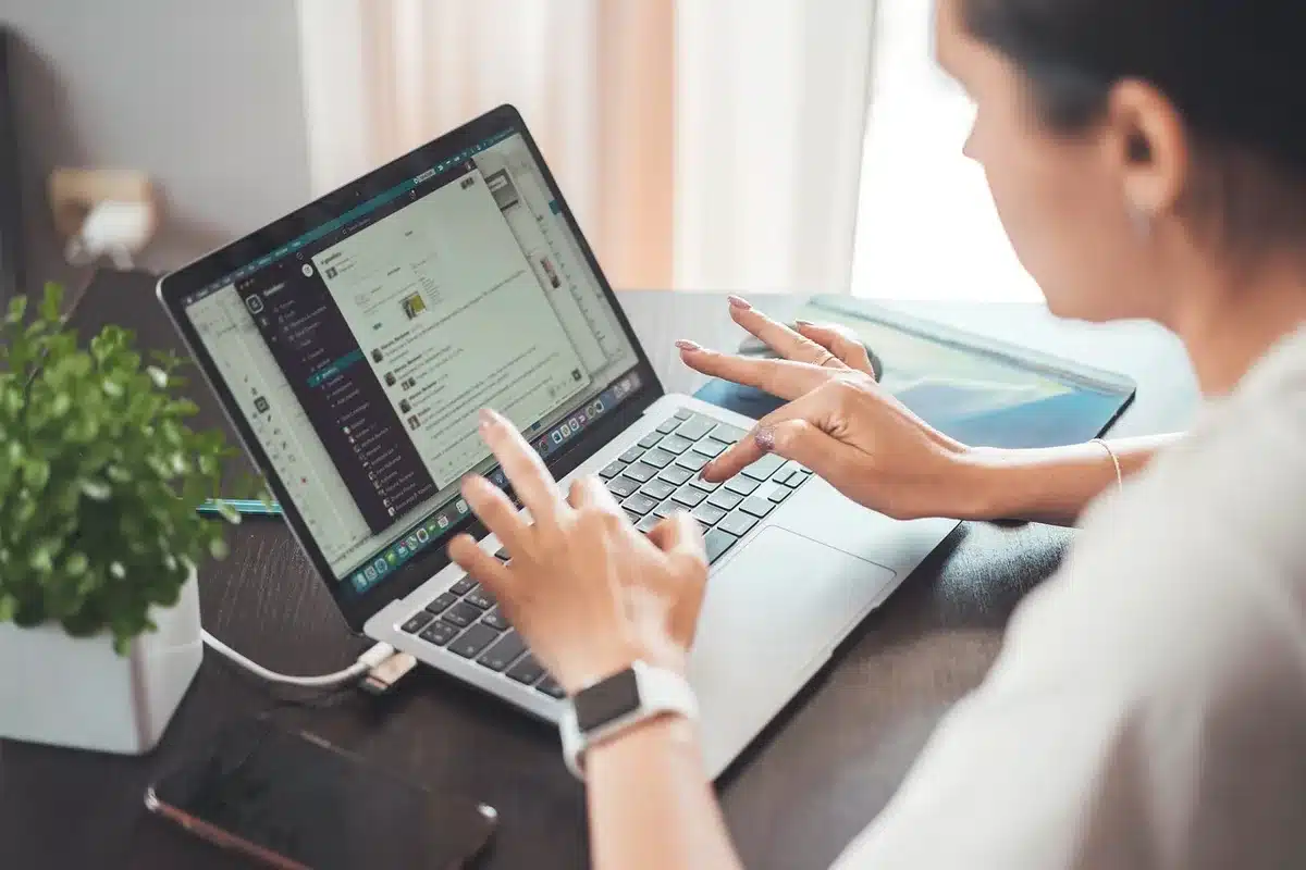 Mani anonime su un portatile con codice e icone di portafoglio digitale sullo schermo