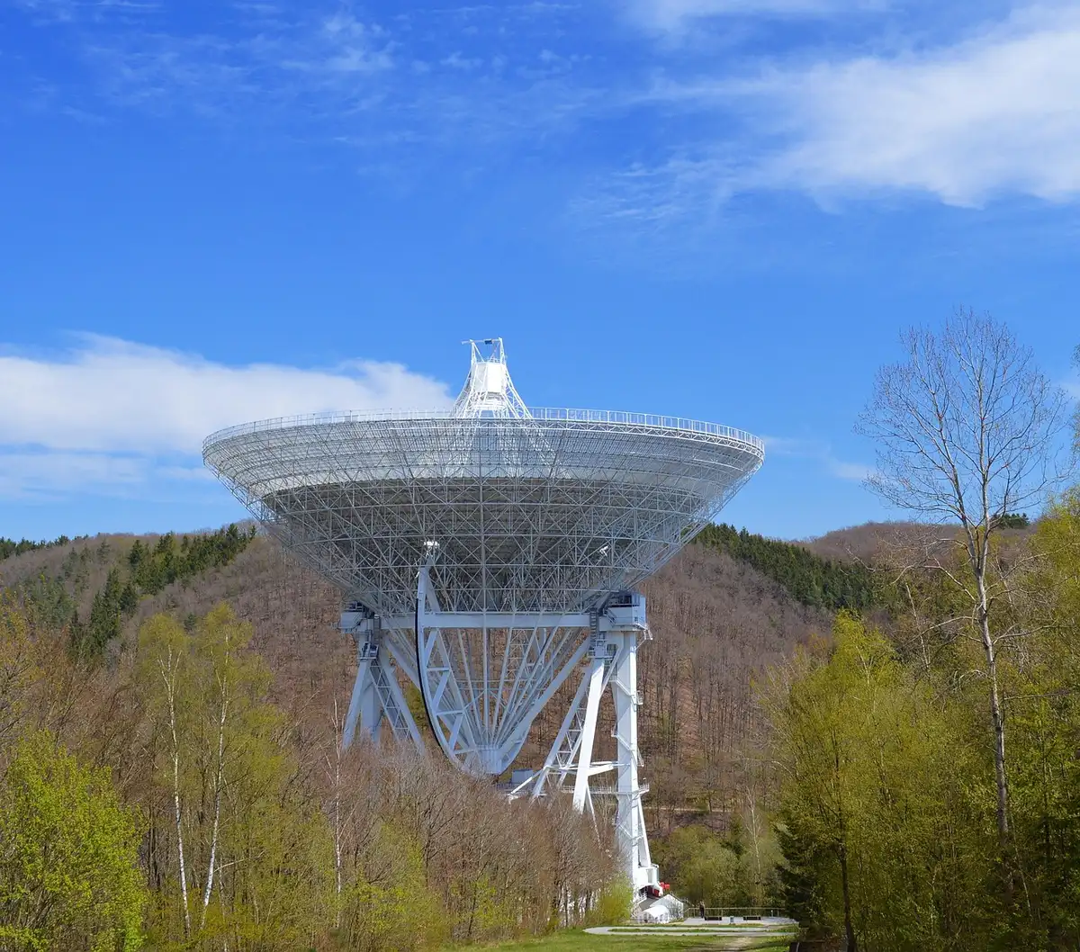 Tecnico anonimo regola uno specchio segmentato in una struttura di assemblaggio spaziale con illuminazione infrarossa.