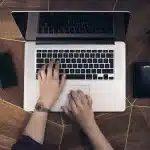 Smartphone, laptop sottile e auricolari su un tavolo di lavoro, senza loghi