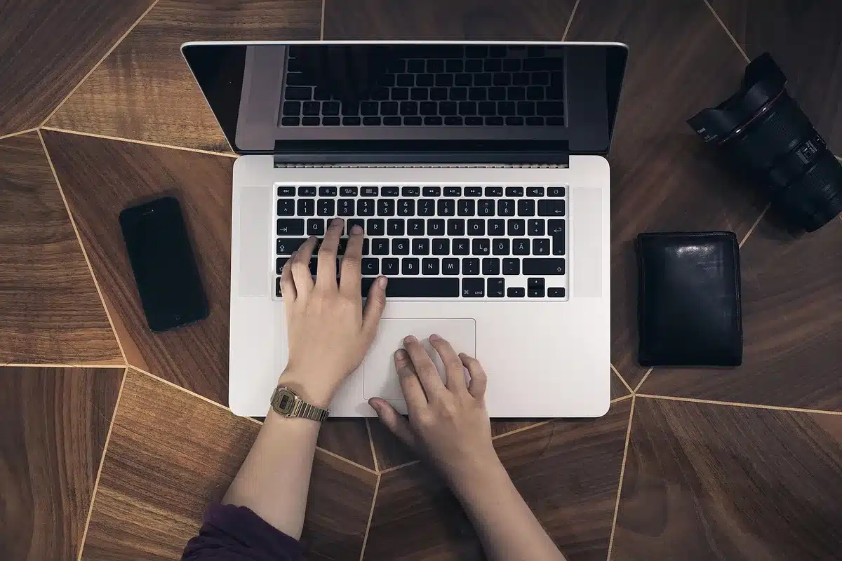 Smartphone, laptop sottile e auricolari su un tavolo di lavoro, senza loghi