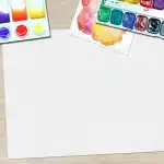 Schermo di un software di design grafico con pannelli di strumenti e livelli aperti su una scrivania luminosa