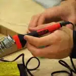 Mani guantate che saldano direttamente i cavi sulla scheda PCB di una GPU con ferro da saldatura