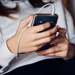 Mani anonime che scorrono una playlist con grafiche di onde sonore su uno schermo