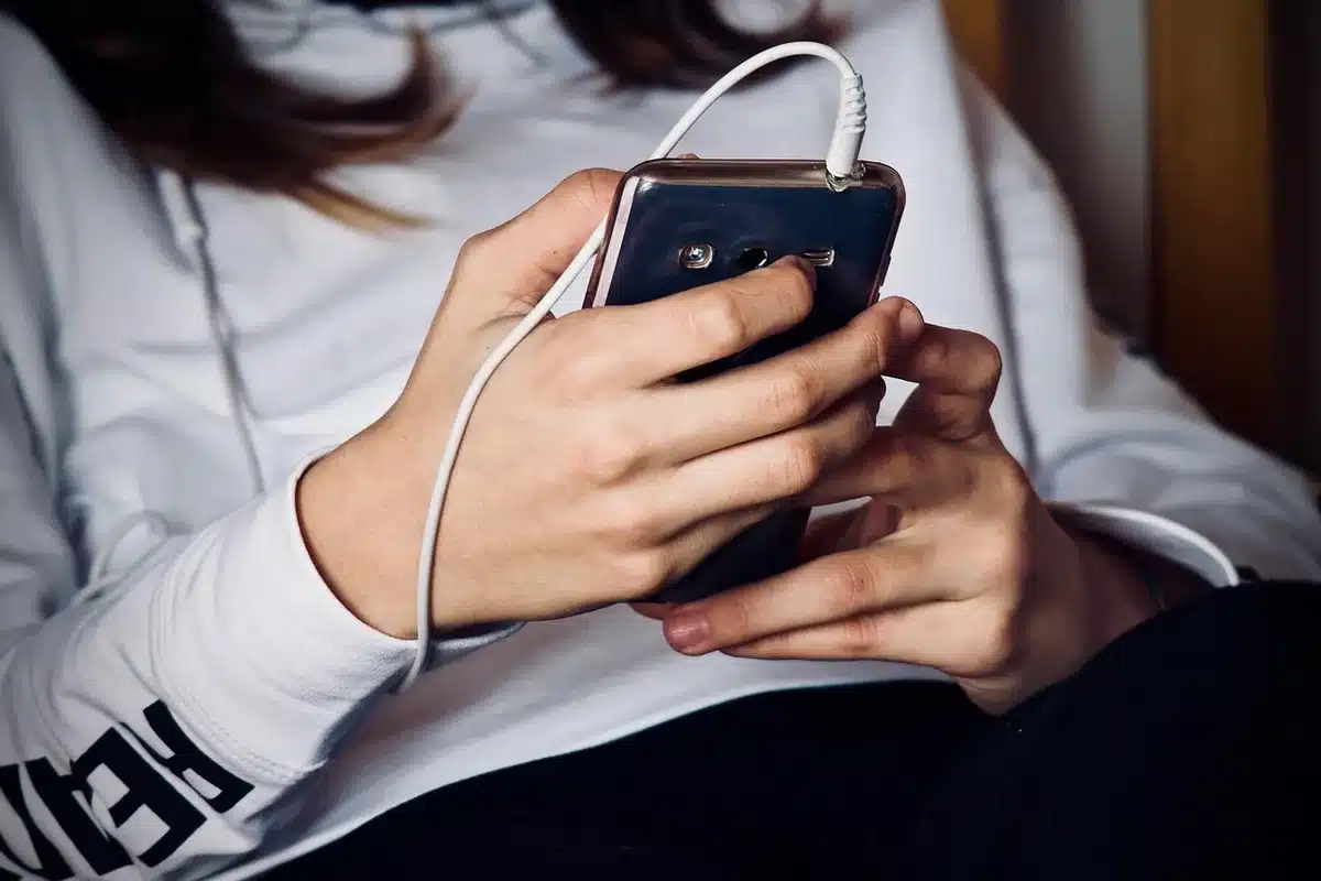 Mani anonime che scorrono una playlist con grafiche di onde sonore su uno schermo