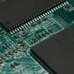 Primo piano anonimo di una scheda GPU prototipo e moduli memoria su un tavolo da laboratorio