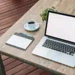 Laptop anonimo con schermo luminoso e tablet su un tavolo in ufficio moderno