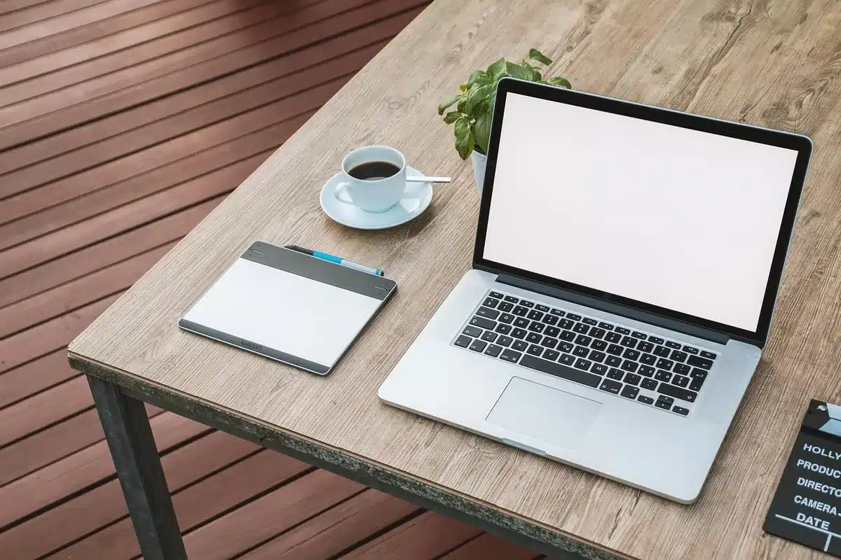 Laptop anonimo con schermo luminoso e tablet su un tavolo in ufficio moderno