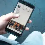 Mani anonime con uno smartphone e documenti sul tavolo che evocano furto d'identità