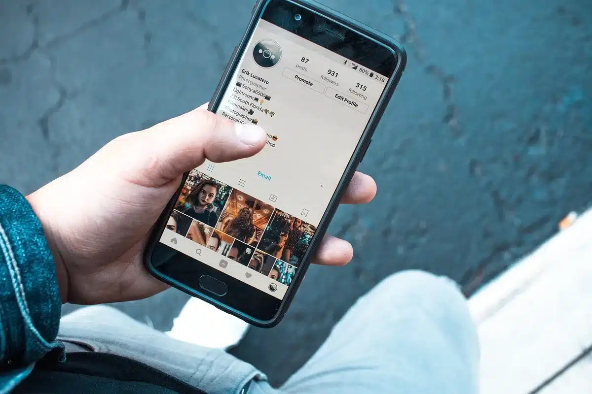 Mani anonime con uno smartphone e documenti sul tavolo che evocano furto d'identità