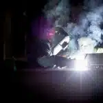 Capannone industriale con robot umanoide in silhouette e operaio di spalle