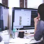 Sviluppatore anonimo al lavoro su shader GPU con codice e schede elettroniche sul tavolo