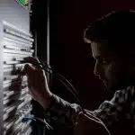 Mani anonime che collegano cavi davanti a rack di server in un data center