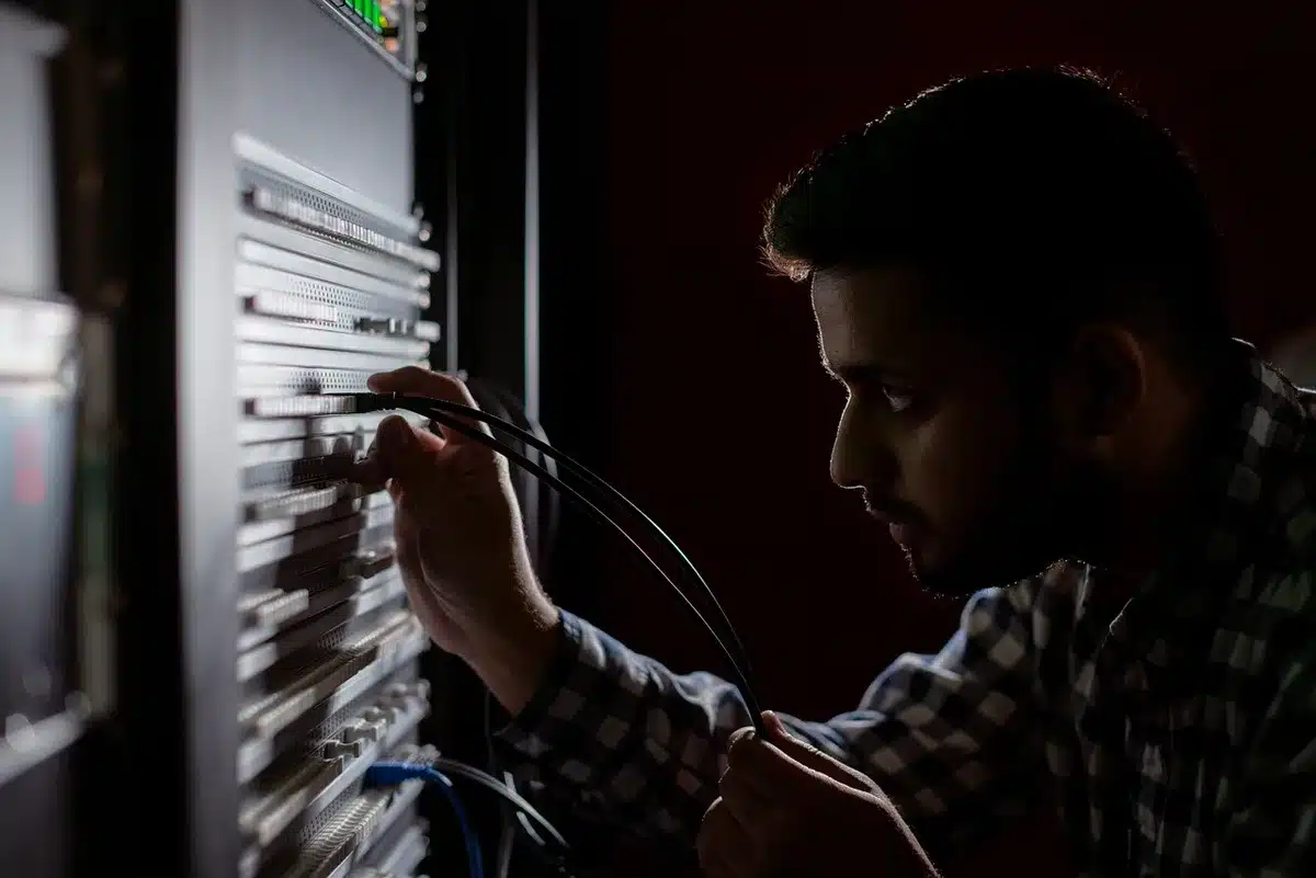 Mani anonime che collegano cavi davanti a rack di server in un data center